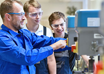 teachershowing students how to use a drill in a woodshop class