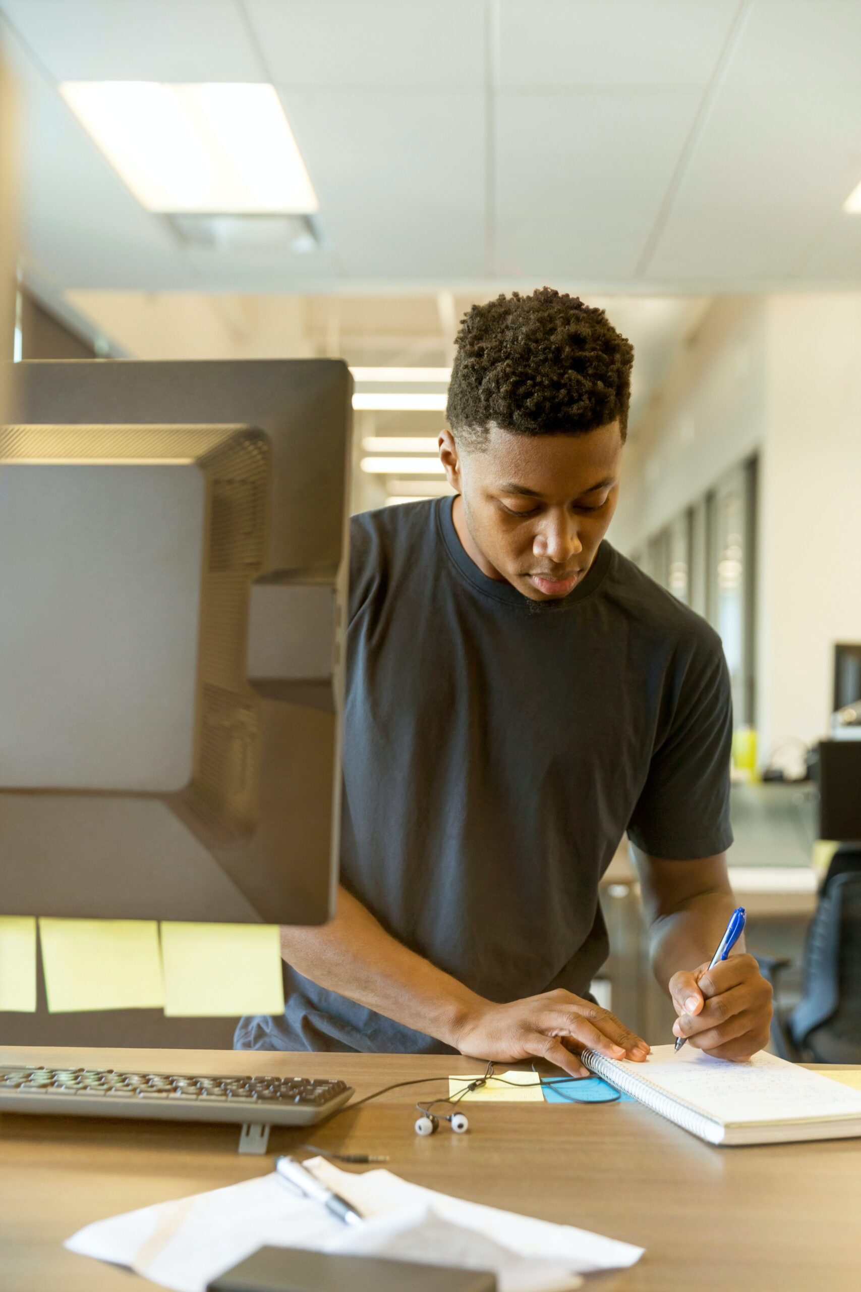 Person taking notes in front of computer